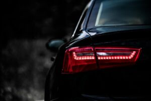 Dramatic close-up shot of a sleek modern car tail light in dark ambiance.