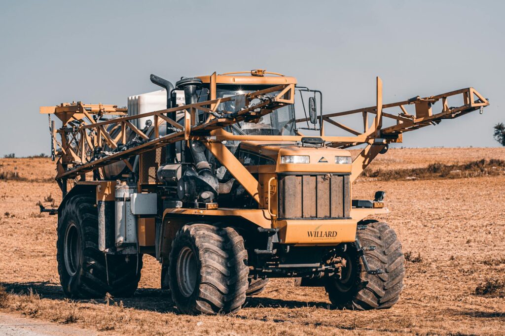 A self-propelled agricultural sprayer in a vast field showcasing modern farming technology.