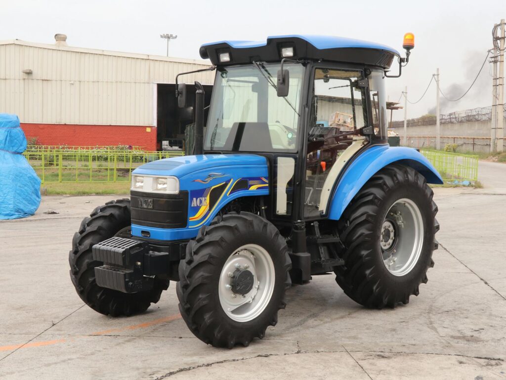A powerful blue 4WD tractor parked outdoors in an industrial area, showcasing modern agricultural equipment in India.